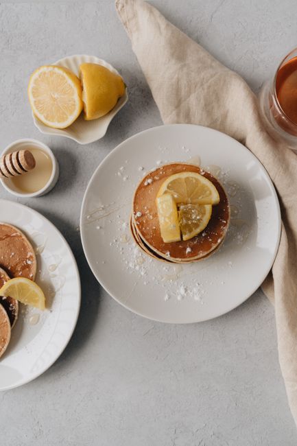 Stack of pancakes with lemon slices and honey, perfect for a breakfast treat.