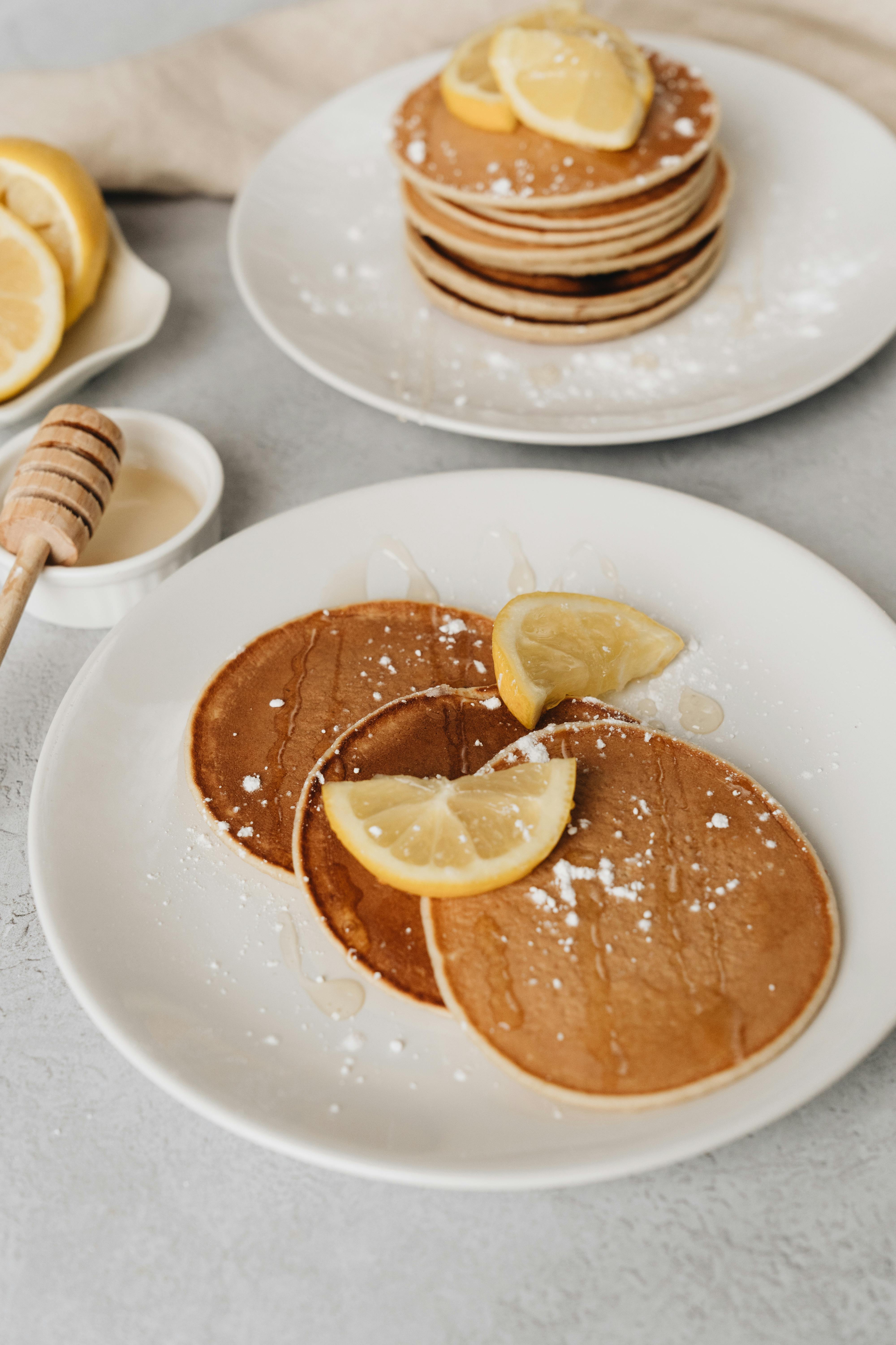 Delicious lemon pancakes topped with honey and powdered sugar, perfect for breakfast.