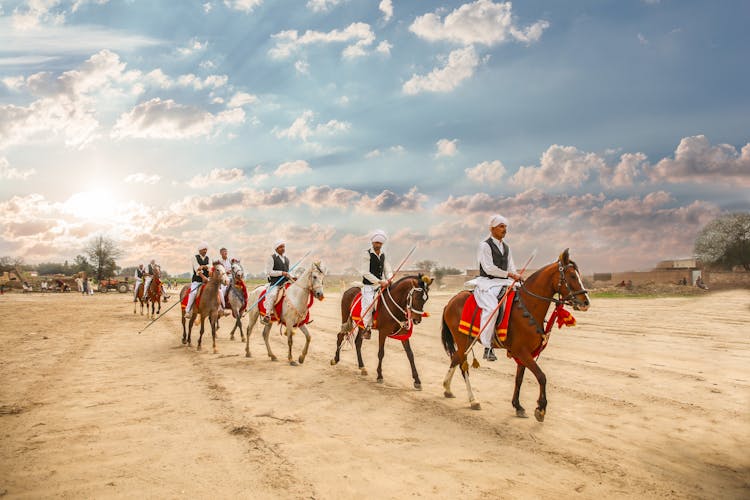 Men Riding Horses On Brown Sand