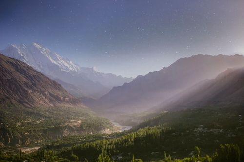 Free Serene mountain valley with snowcapped peaks under a starry night sky, shrouded in mist. Stock Photo