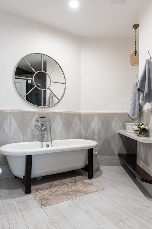 White clean bathtub under round shaped mirror