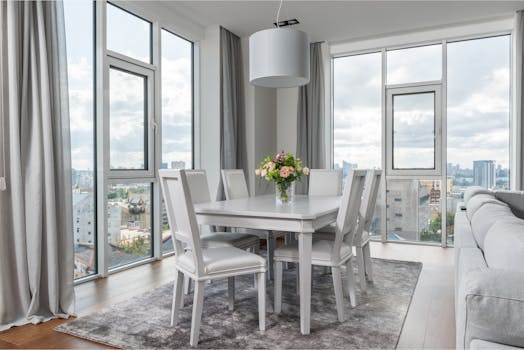 A contemporary dining room with cityscape views, elegant design, and a floral centerpiece.