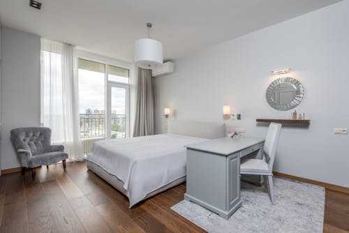 Interior of contemporary bedroom with comfortable bed and light furniture placed in modern apartment in daylight