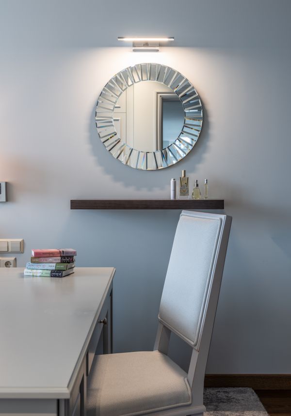 Slim work table with a stack of books and a chair against a plain wall — photo by Max Vakhtbovych on Pexels