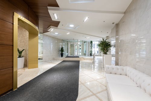 Interior of contemporary spacious lobby without people with white leather sofa and long black carpet