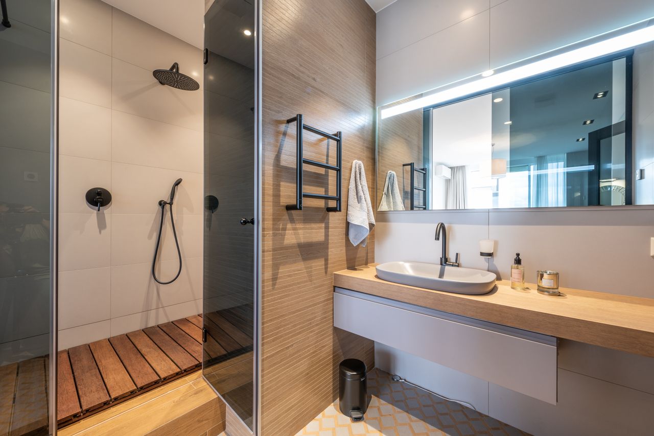 Walk-in shower with warm wood slat flooring, black rainfall fixtures and wood-paneled walls