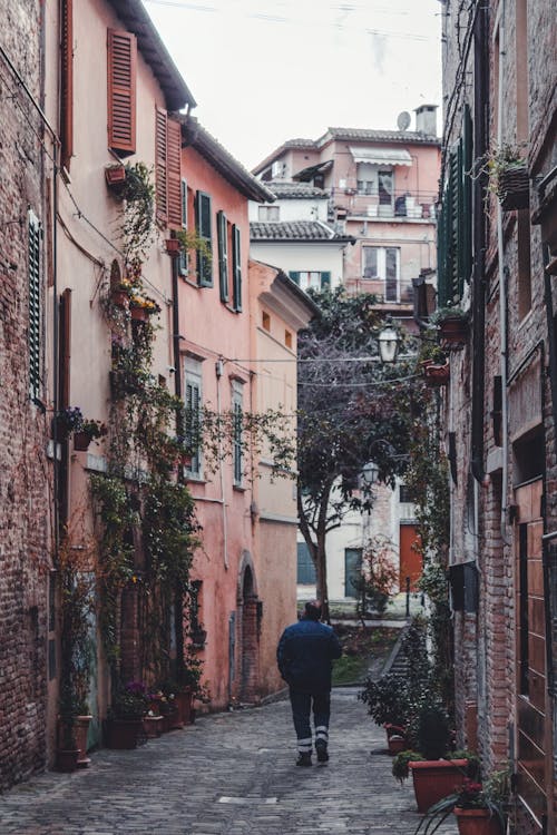 Back View of a Person Walking on a Narrow Street