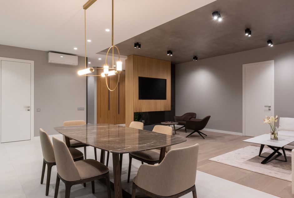 Bright modern dining area with ceiling lamps suspended above a wooden table surrounded by armchairs.