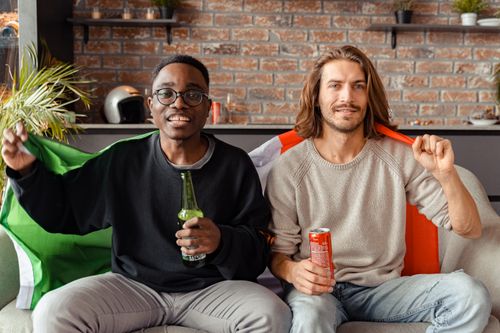 Free Two friends enjoying drinks and celebrating with flags indoors. Stock Photo