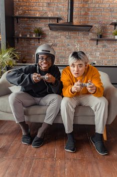 Two young men intensely playing video games on a sofa indoors.