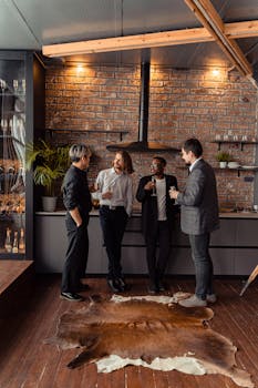 Four diverse adults enjoy a casual meeting in a stylish indoor lounge with brick walls.