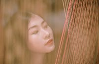 这幅宁静的肖像描绘了一位女性透过垂直的纱线凝视的画面，营造出梦幻般的效果