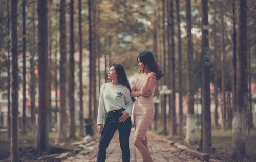 Free Two young women enjoying a stroll along a tree-lined path on a beautiful fall day. Stock Photo