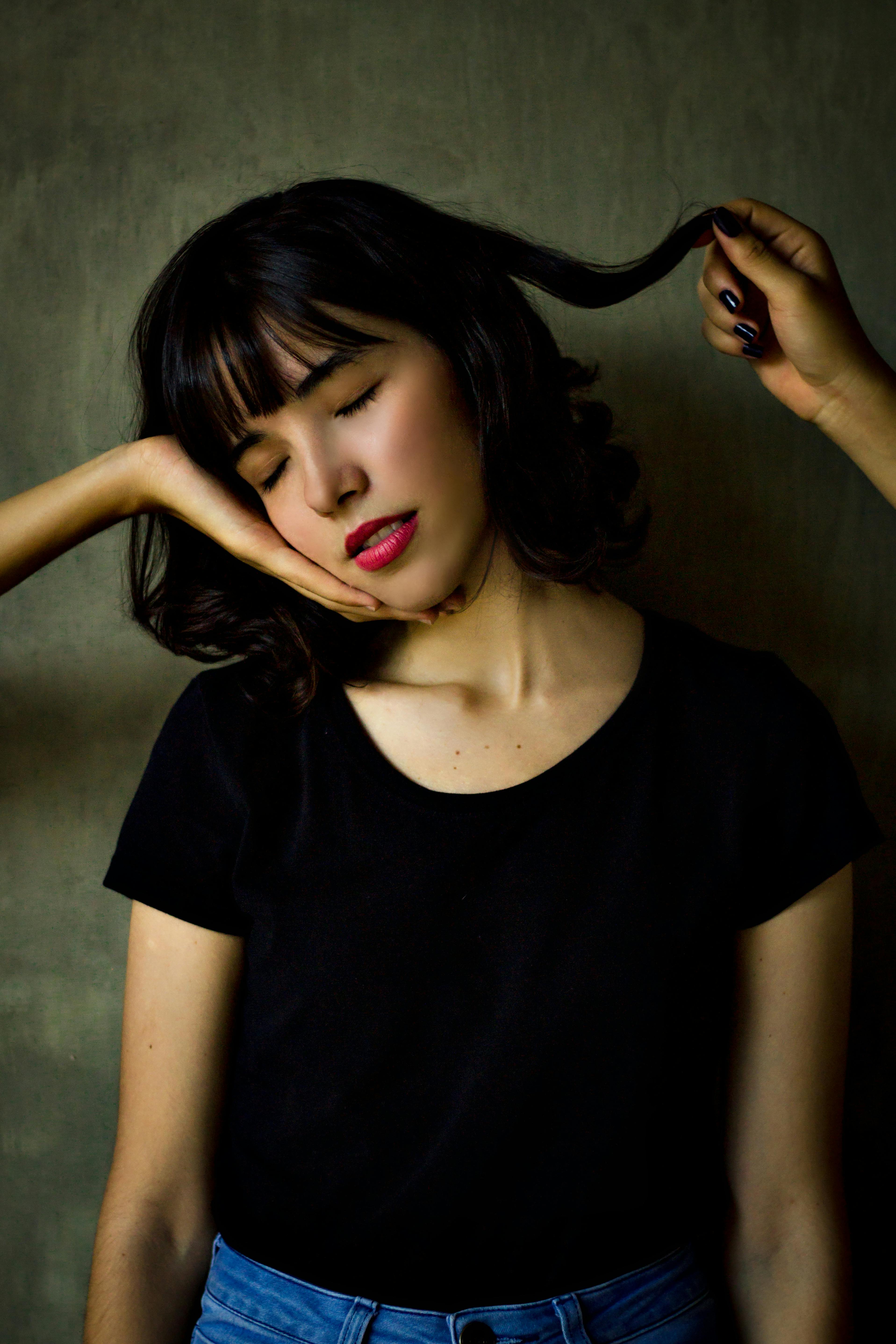 Artistic portrait of a young Asian woman indoors, expressing contemplation and beauty.