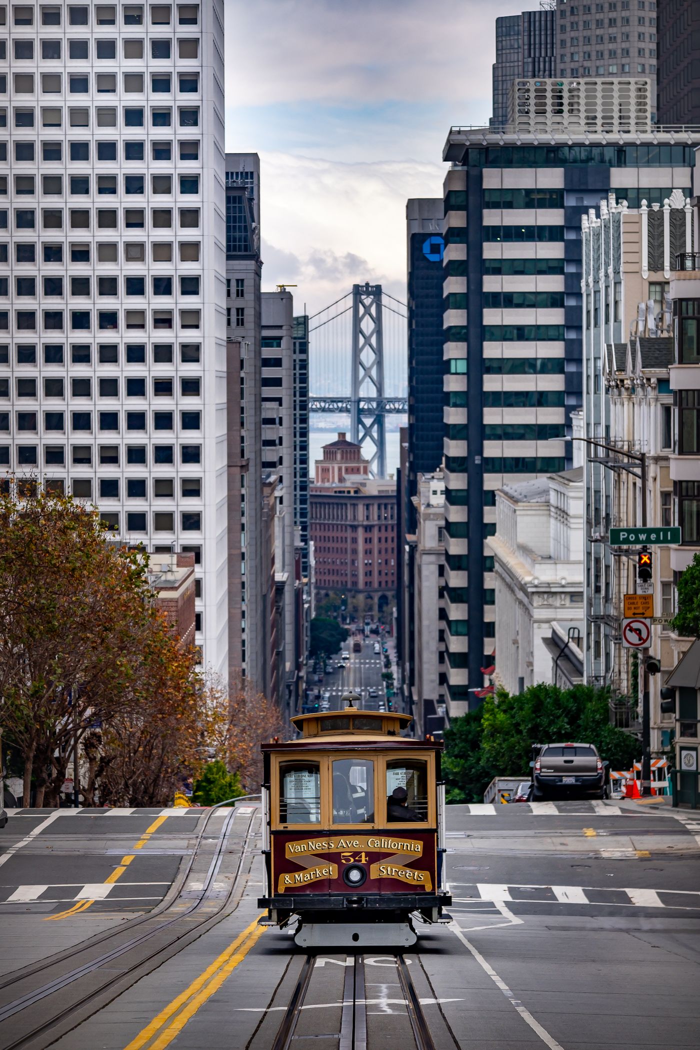 Vista de una calle en pendiente de San Francisco con un cable car y edificios al fondo