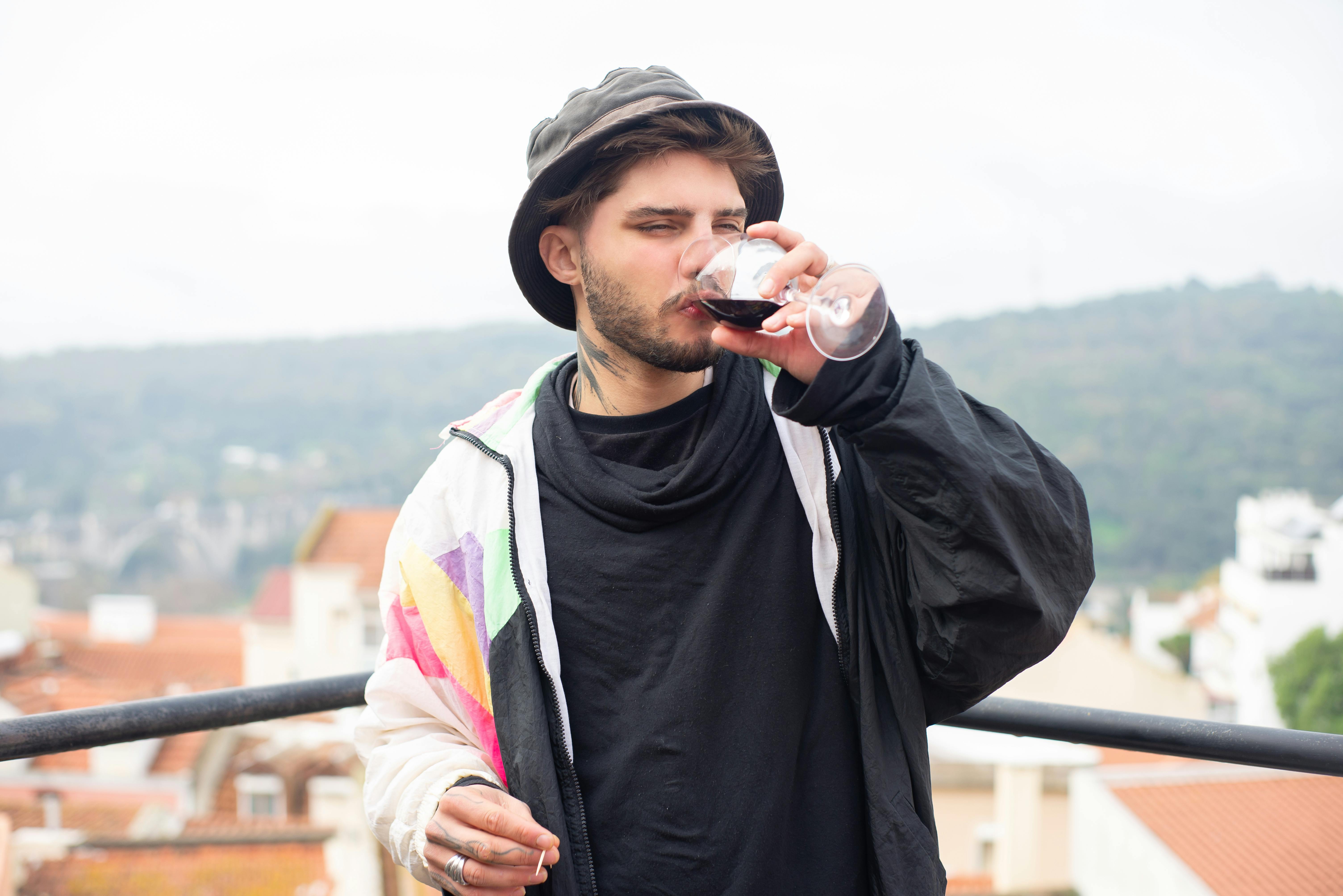 Young man with beard savoring wine on a scenic rooftop in Portugal.