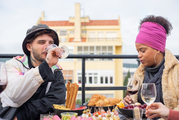 Group Of Young People Eating Snacks And Drinking Wine On A Terrace 