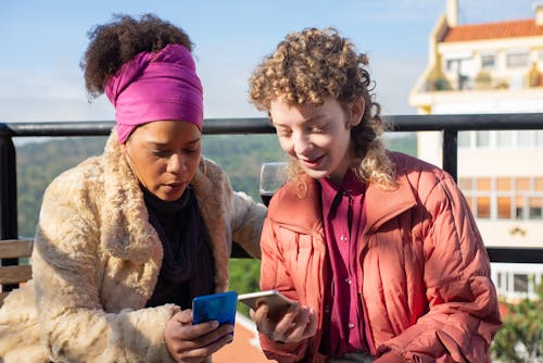 Free Women Sitting Looking at Their Smartphone  Stock Photo