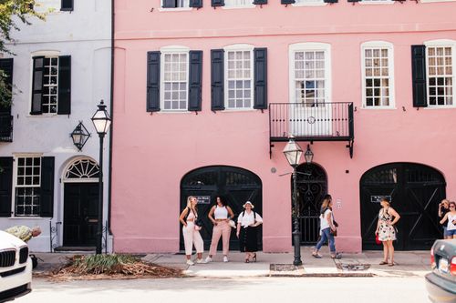 Free Vibrant street in old town featuring pink building facade and pedestrians enjoying a sunny day. Stock Photo