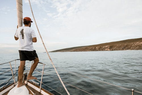 Free Man Standing in Front of a Sailboat Stock Photo