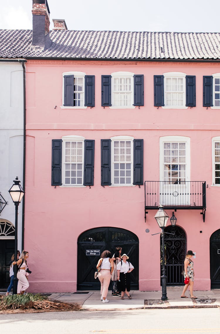 People Walking Beside A Pink Apartment Building