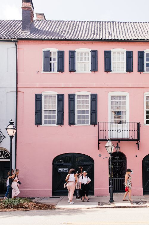 Free Group walking by a charming pink building in Charleston's historic district. Iconic and colorful street view. Stock Photo