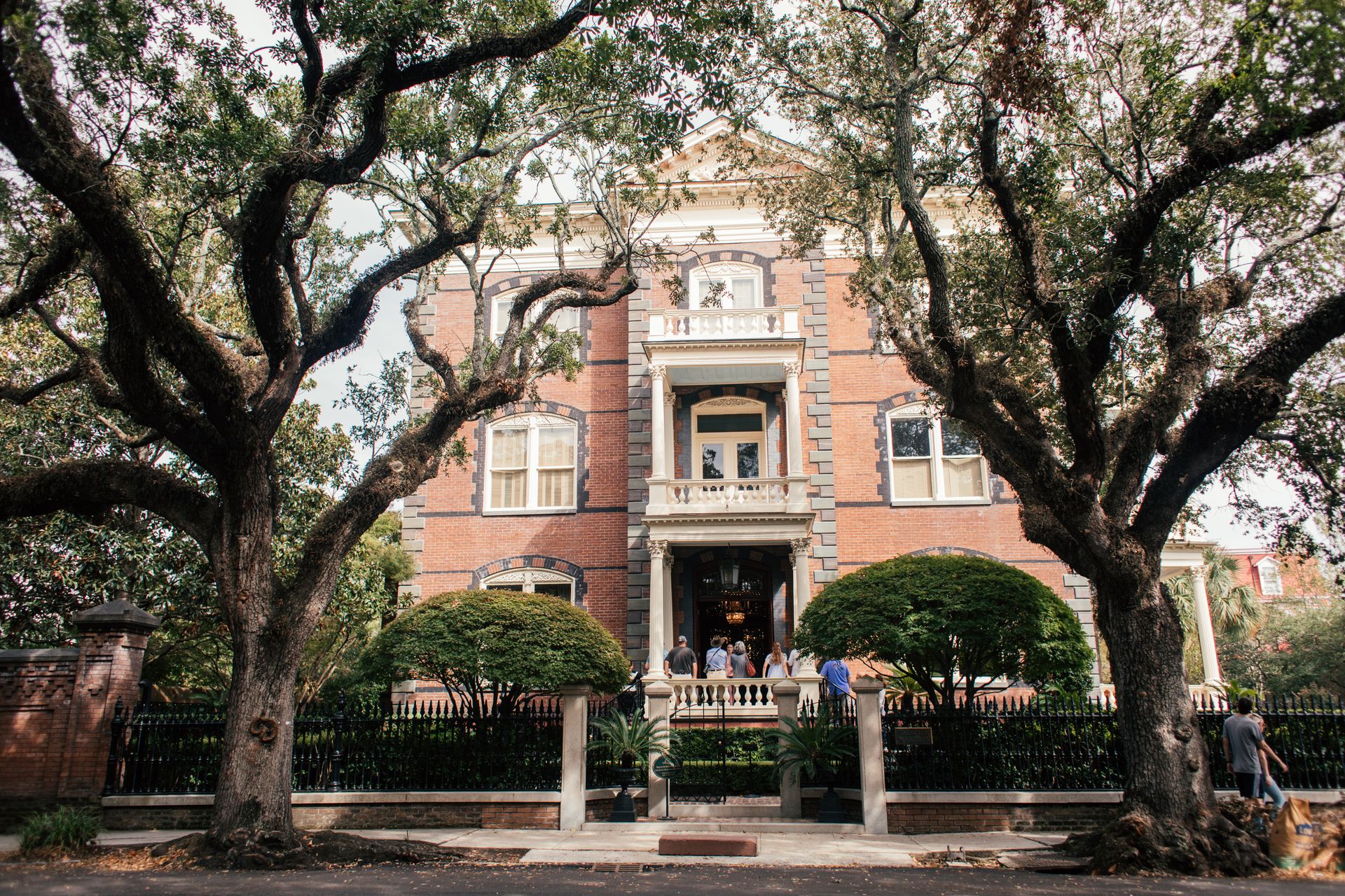 Elegant brick mansion exterior with trees and entrance, captured in daylight.