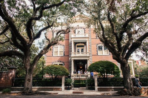 Free Elegant brick mansion exterior with trees and entrance, captured in daylight. Stock Photo