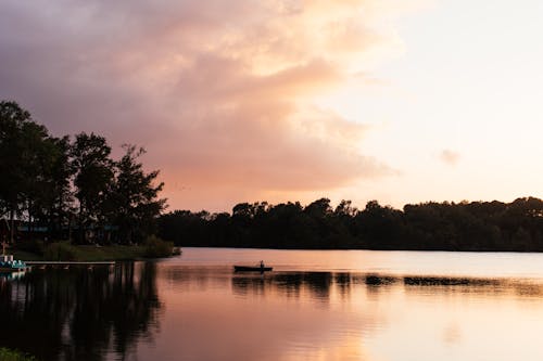 Silhouette of a Boat Sailing on the River During Sunset