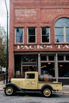 A classic vintage truck parked outside a historic tavern with red brick facade.