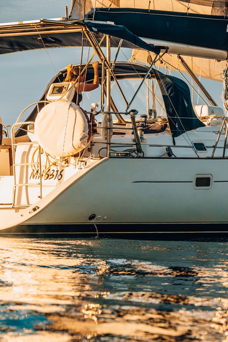 Woman Sitting On A White Boat Sailing On The Water