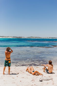 Group of friends enjoying a sunny day on a sandy beach by the vibrant sea.