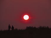 夕阳下，一对夫妇散步的剪影映在天空中，太阳充满活力地落下