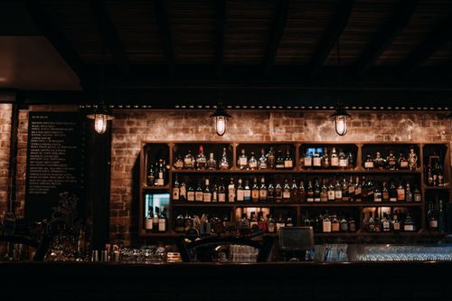 Free Warm and inviting bar interior showcasing a variety of liquors on wooden shelves. Stock Photo