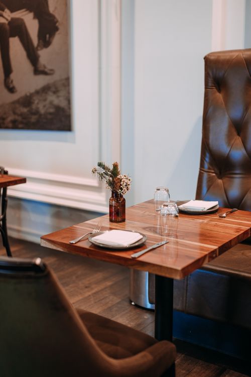 Free Fine dining table setup in a modern restaurant with wooden furniture and floral decor. Stock Photo