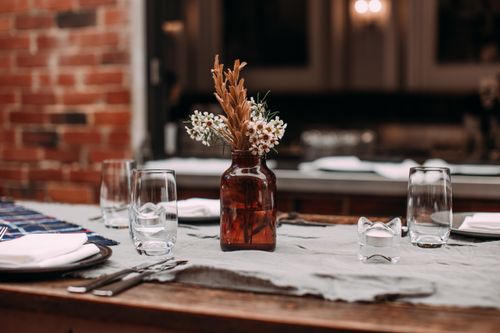 Free Charming rustic table setting with glassware, cutlery, and a floral centerpiece in an amber bottle. Stock Photo