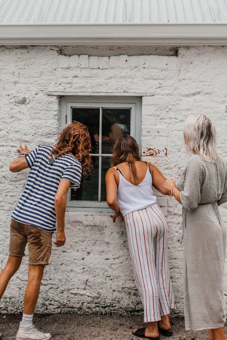 People Peeking Inside A House Through A Window