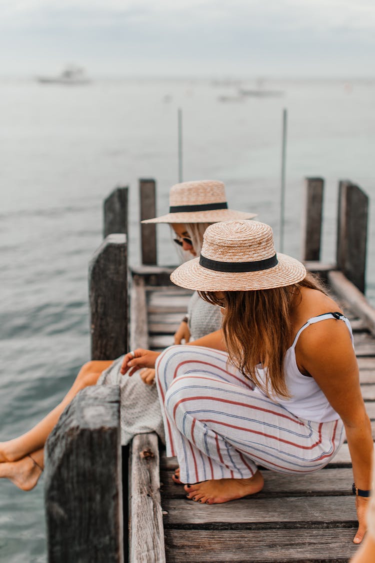 Women Sitting Together On A Wooden Dock