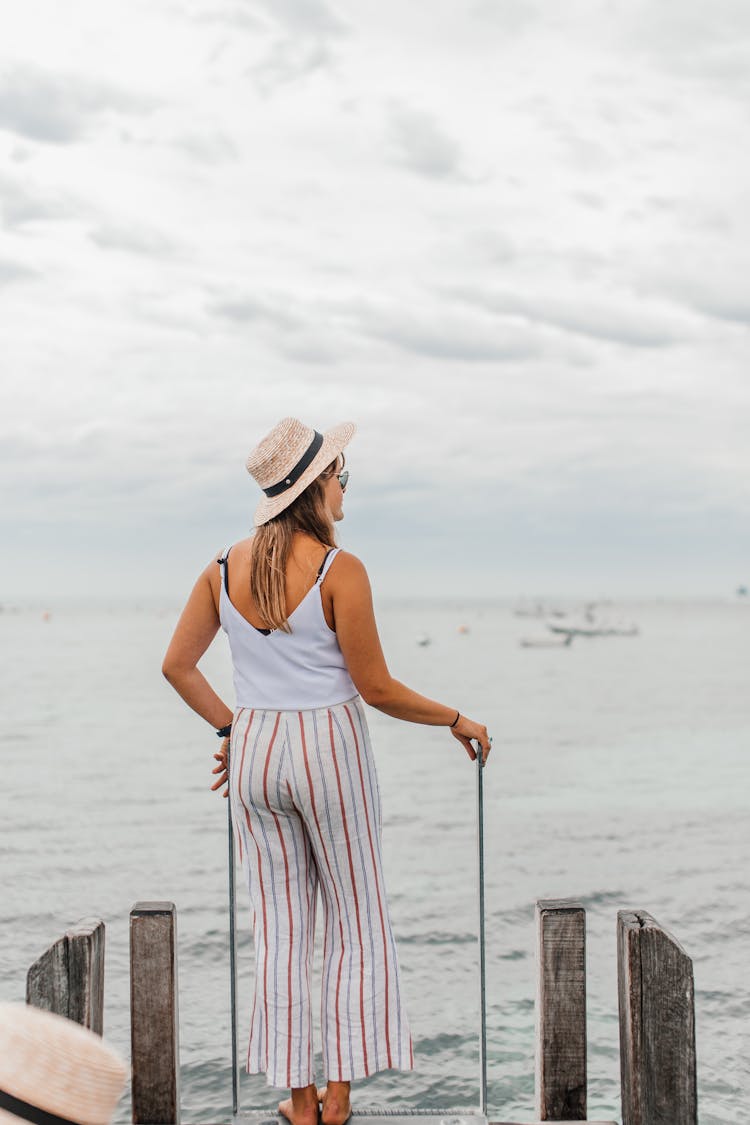 A Woman Standing At The Edge Of A Wooden Dock