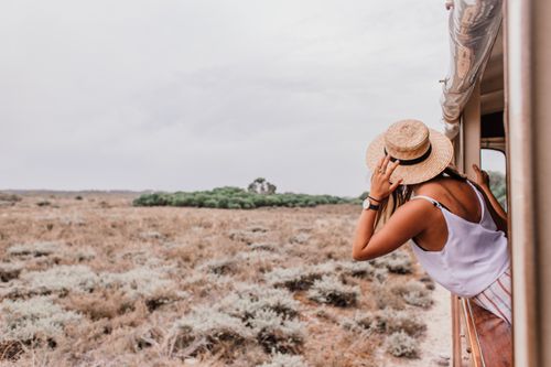 Free Woman with straw hat looking out train window at scenic countryside. Adventure awaits. Stock Photo