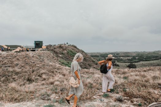 Two women explore a hilly landscape, capturing a sense of adventure and freedom in the wild outdoors.