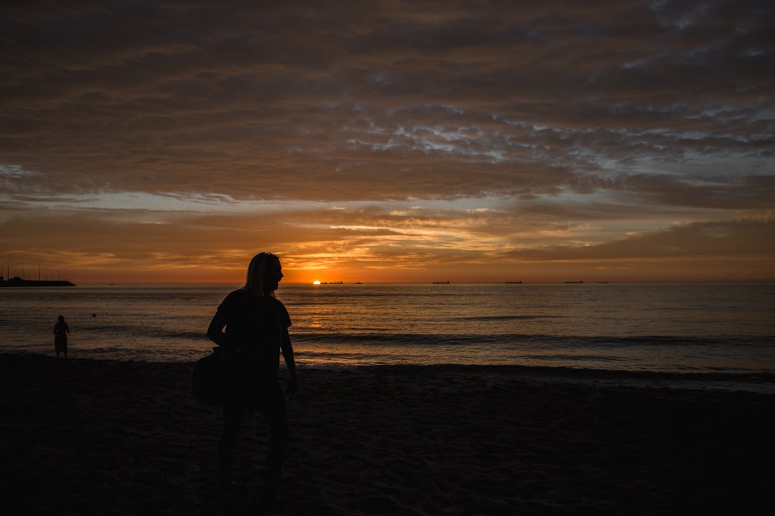 A Silhouette of a Woman Walking at the Beach