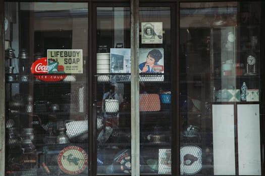 A vintage storefront showcasing retro items like signs, tins, and decor through window.