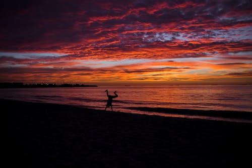 Silhouette of a Person Doing Cartwheel on Shore