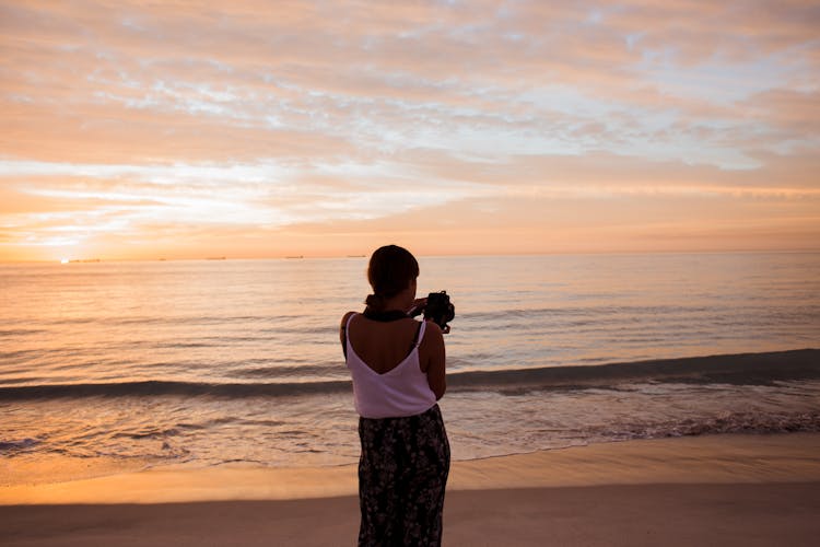 Woman Photographing Sea At Sunset