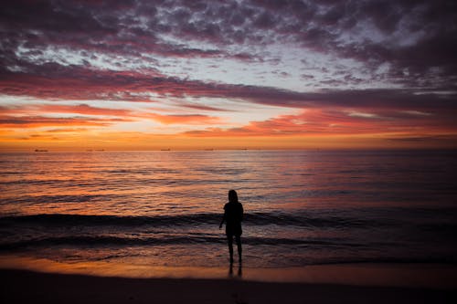 Woman Standing on a Beach at Sunset 