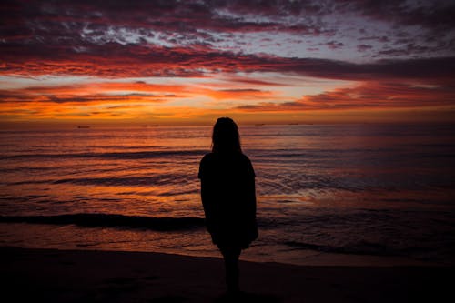 Woman Standing on a Beach at Sunset 