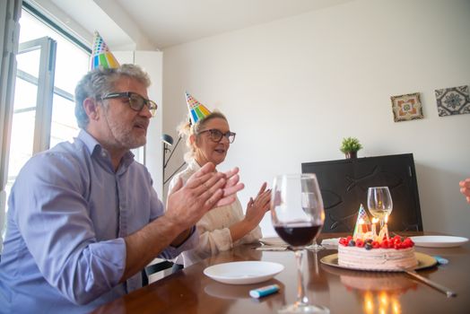 Two adults celebrating a birthday indoors in Portugal with cake and wine.