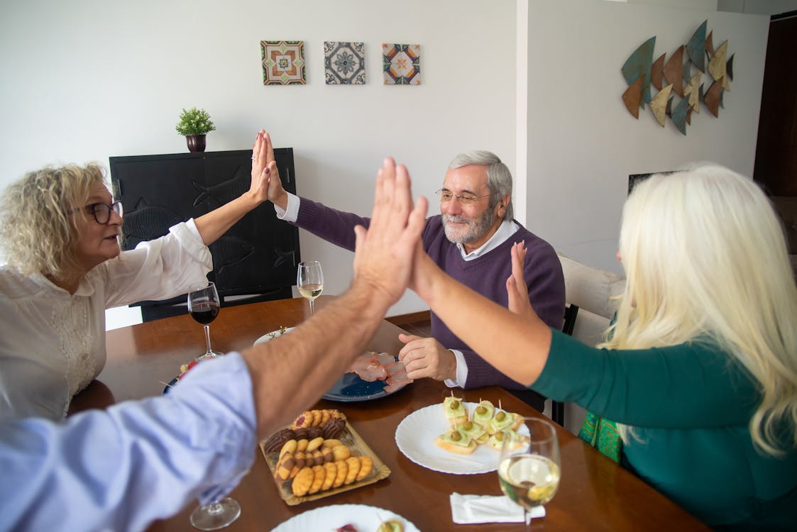 People High-Fiving Each Other at Dinner · Free Stock Photo