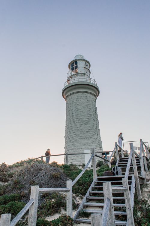 Free A towering lighthouse with wooden stairs under a blue sky, low angle view. Stock Photo